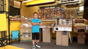 Caine standing in front of his home made cardboard arcade